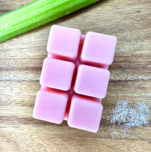 Load image into Gallery viewer, Six pink square wax melts arranged in a 2x3 grid on a wooden surface, with a green stalk of rhubarb and a small pile of white sugar in the background.