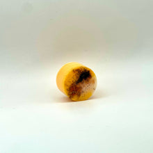Load image into Gallery viewer, A small round yellow-orange wax melt with dark brown speckled areas, photographed on a plain white studio background.
