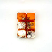Load image into Gallery viewer, A small rectangular wax melt  made of six square pieces, featuring a dual-tone design with bright orange top sections and textured silver and dark gray bottom sections, displayed on a white surface.
