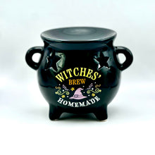 Load image into Gallery viewer, A glossy black witch cauldron-shaped decorative wax melt burner with star cutouts and the words 'WITCHES BREW HOMEMADE' in yellow, white, and lavender on the front, photographed on a clean white background.

