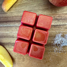 Load image into Gallery viewer, Six red wax melts arranged in a 2x3 grid on a wooden surface, with partial fruit slices and a sprinkle of coarse sugar visible around them.
