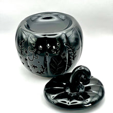 Load image into Gallery viewer, A glossy black ceramic pumpkin-shaped wax melt burner with a matching lid, featuring carved floral and leaf patterns, photographed on a white background.

